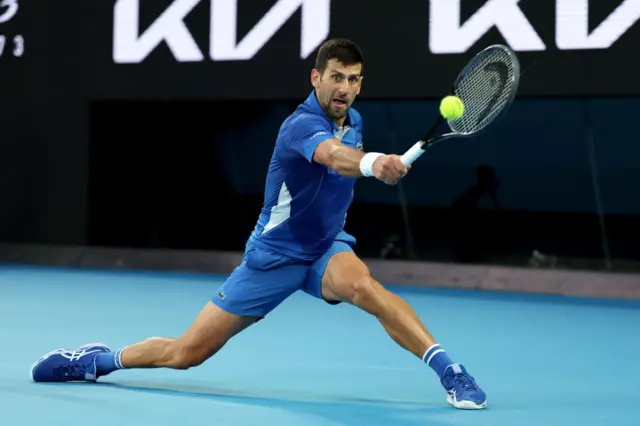 Novak Djokovic slides to hit a backhand shot