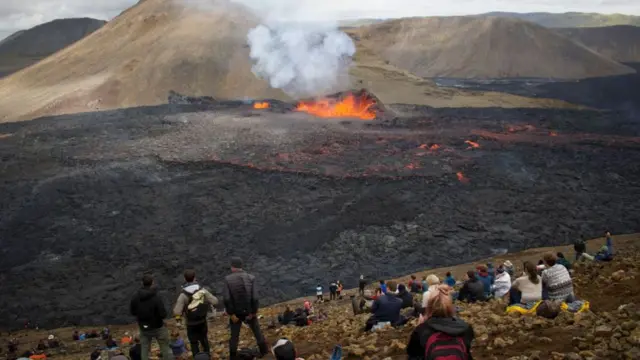 Onlookers watch as lava flows from the volcano in Fagradalsfjall, Iceland, around 40 kilometres (25 miles) from the capital Reykjavik, on 10 August 2022