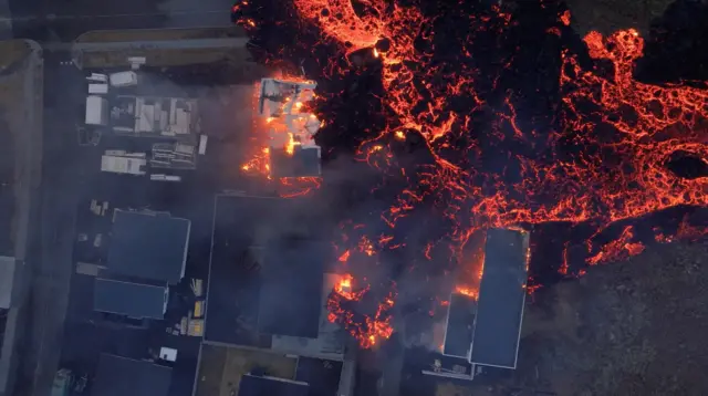 Lava flows from a volcano as houses burn in Grindavik on Sunday