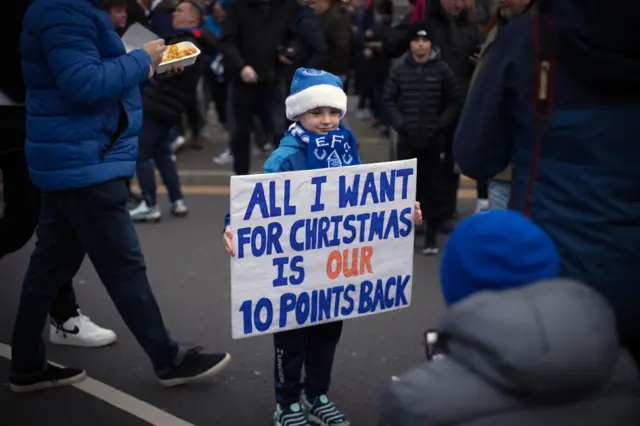 An Everton fan holds a placard saying 'all I want for Christmas is our 10 points back'