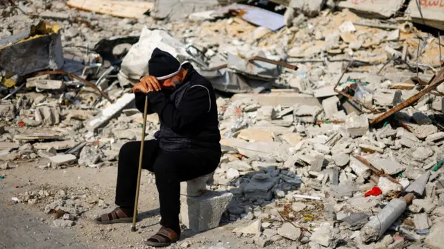 A Palestinian man puts his head in his hands amid rubble in Rafah, Gaza