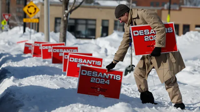 A volunteer plunges campaign signs for Republican Presidential Candidate, Florida Gov. Ron DeSantis into deep snow outside the Chrome Horse Saloon one day before the Iowa caucuses on January 14, 2024 in Cedar Rapids, Iowa