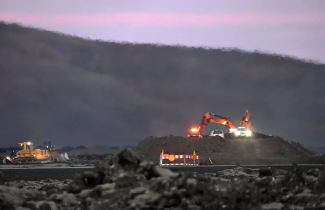 Digger-operators work on a wall built to try and stop lava flowing into Grindavik