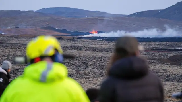 People watching the scene at Grindavik as lava flow and smoke continues