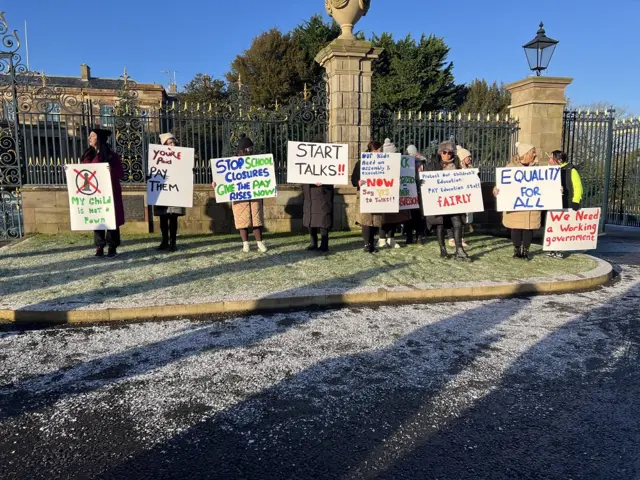 Protesters outside Hillsborough Castle with signs