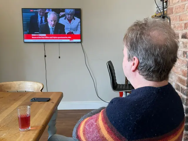 Scott Darlington watches a TV screen in his home