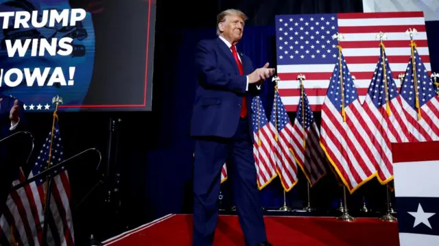 Donald Trump applauds as he stands on his campaign stage in Iowa