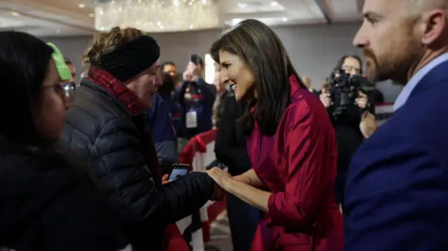 Haley holds the hand of a woman, smiling at her