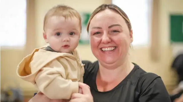 Mother-of-two Stacy Young holding her six-month-old son and smiling