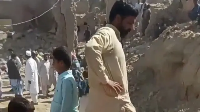 People in an Iranian village near the Iran-Pakistan border looking through the rubble after Pakistan's attack