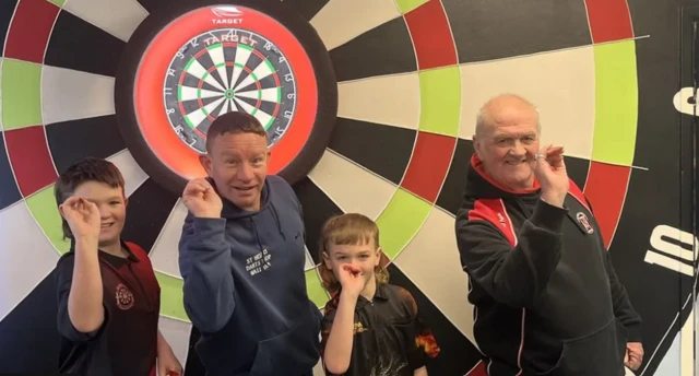 George, nine, and Jack Evans, 11, with their coach Karl Holden and grandfather Danny Rylance at St Helens Darts Shop, Merseyside