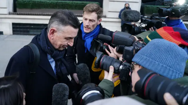 Fujitsu's Paul Patterson is swarmed by photographers outside the Post Office inquiry