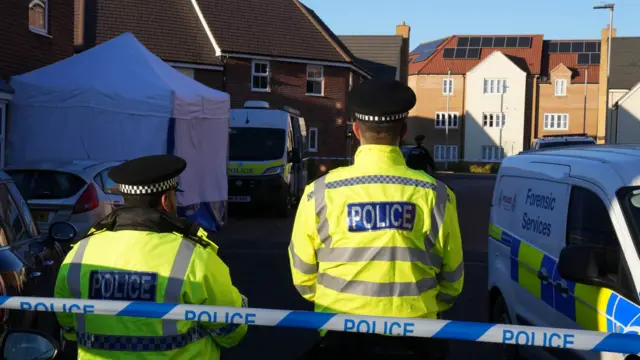 Police vehicles and officers within the cordon