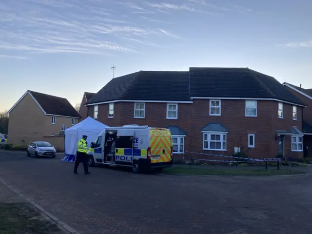 A police van and white tent remain outside the house on Allan Bedford Crescent