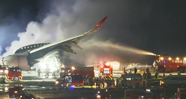 Passenger jet smoulders on Haneda airport's runway