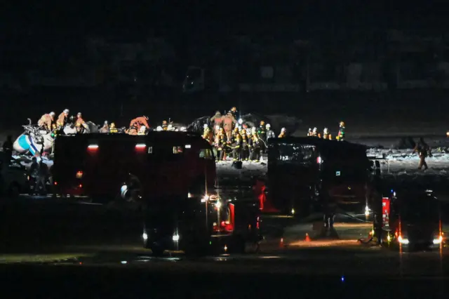 Rescue crews work at the site where a Japan coast guard aircraft collided with a Japan Airlines passenger plane