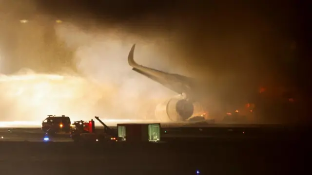 Firefighters work on a burning Japan Airlines' A350 airplane at Haneda International Airport