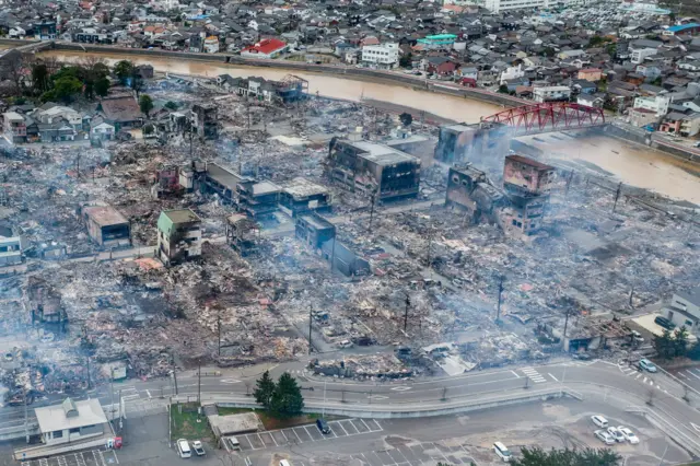 Smoke floats over destroyed buildings in Wajima