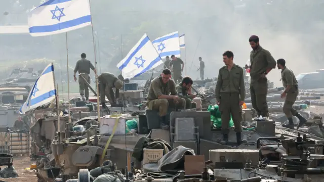 Israeli soldiers stand on tanks near the Israel Gaza border