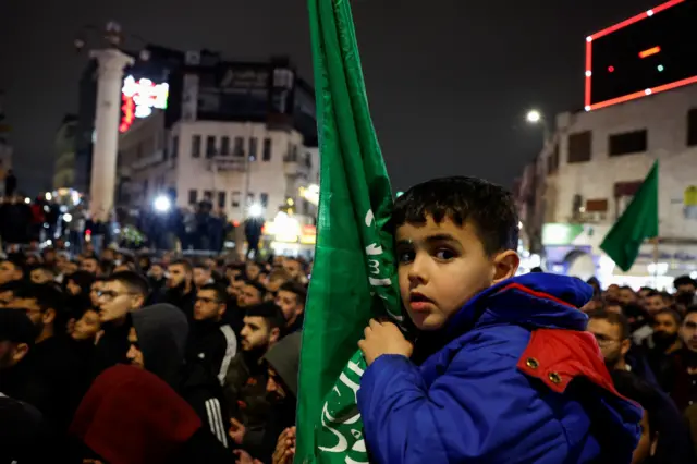 A young boy holding a flag surrounded by a crowd