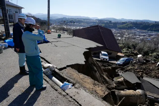 People with helmets looking down at rubble left from the earthquake