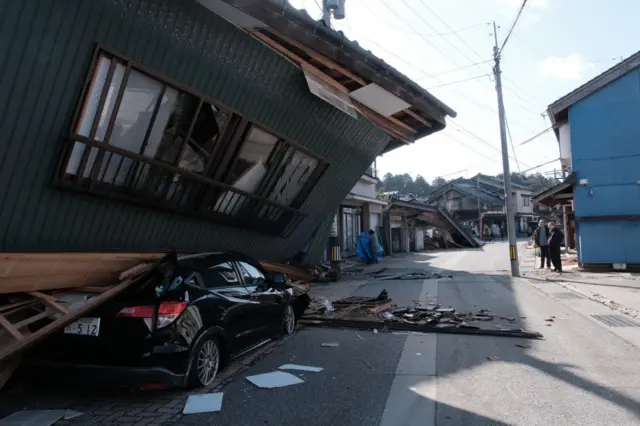 A car is crushed by a collapsed house in Nanao