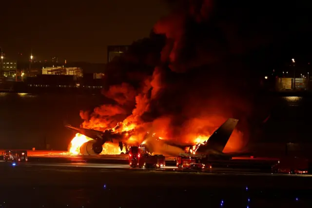 Plane on fire at Japan's Tokyo airport, with fire crews working on the scene