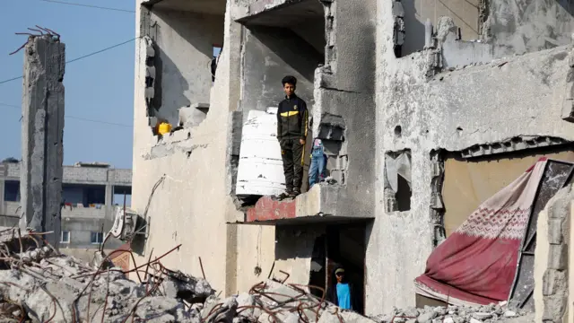 Palestinians stand in a house destroyed by an Israeli strike