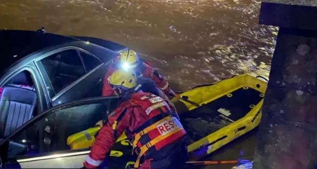 Firefighters rescue occupants of car stuck in flood water