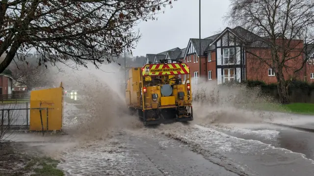 Highway maintenance truck drives through floodwater