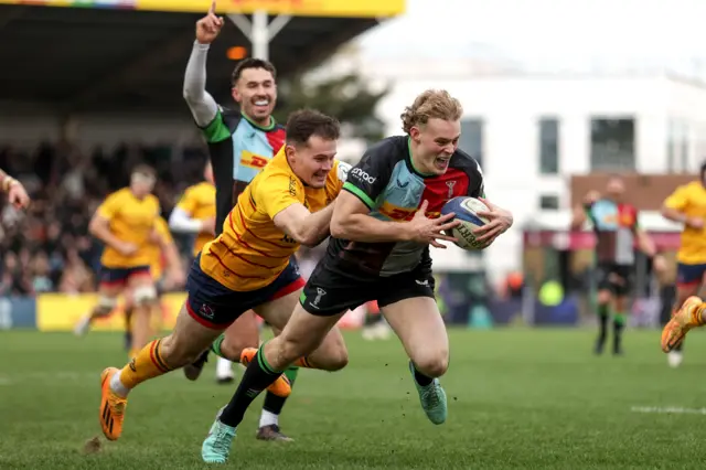 Harlequins' Louis Lynagh scores a try despite pressure from Jacob Stockdale.