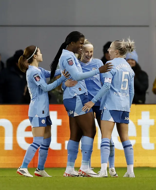 City players huddle to celebrate pulling level via an own goal.