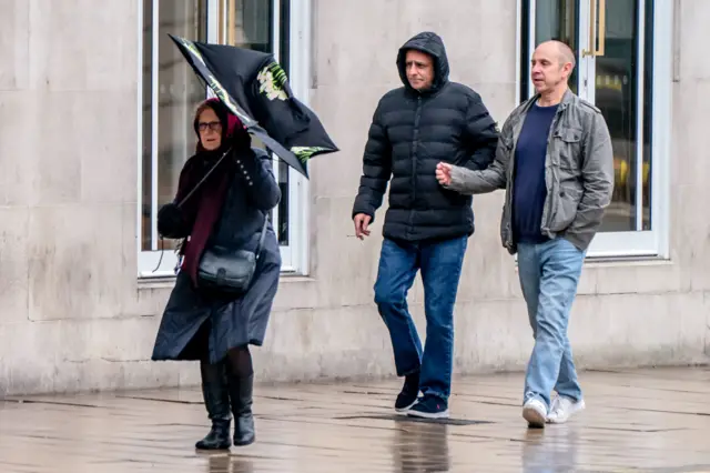 A woman struggles with her umbrella in Leeds