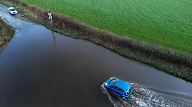 A car drives through flood water after heavy rain from Storm Isha, Swynnerton, Staffordshire