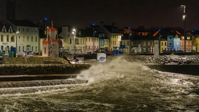 Waves hit a coastline - with houses in the background