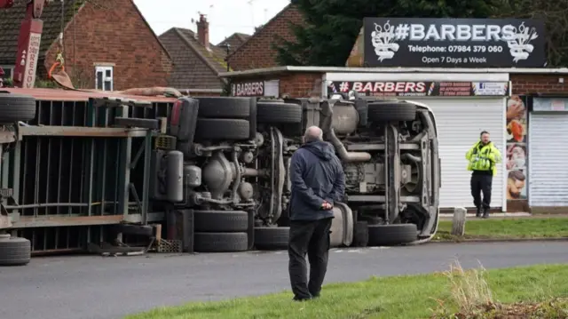 A man looks at a lorry overturned during Storm Isha in Doncaster