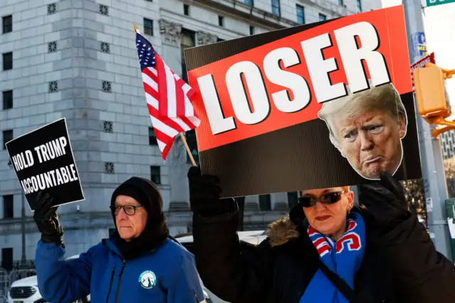 Protesters hold up placards outside the court