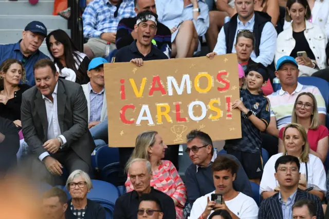 Fan holds 'Vamos Carlos' sign in the crowd