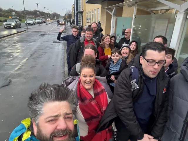 Philip Walker takes a selfie with a group of others, some of whom are smiling