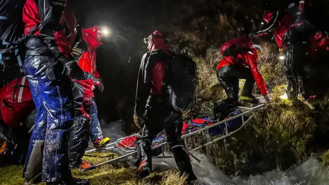 Mountain rescue volunteers traversing the fells in the dark with head torches during a rescue