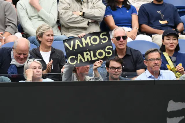 Fan holds 'Vamos Carlos' sign in the crowd