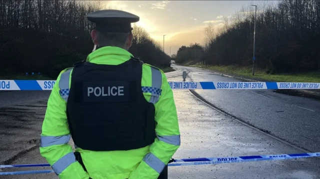 A PSNI officer standing in front of a police cordon