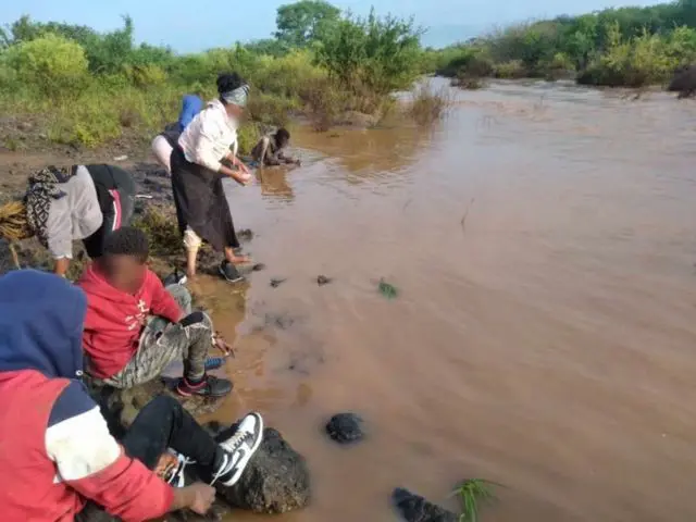 People beside a dirty pool of water