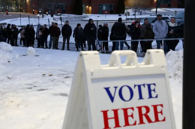 People line up to vote in the snow in Derry, NH, during the 2024 Republican presidential primary