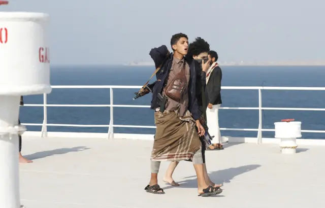 Armed Yemenis tour the deck of the Galaxy Leader cargo ship