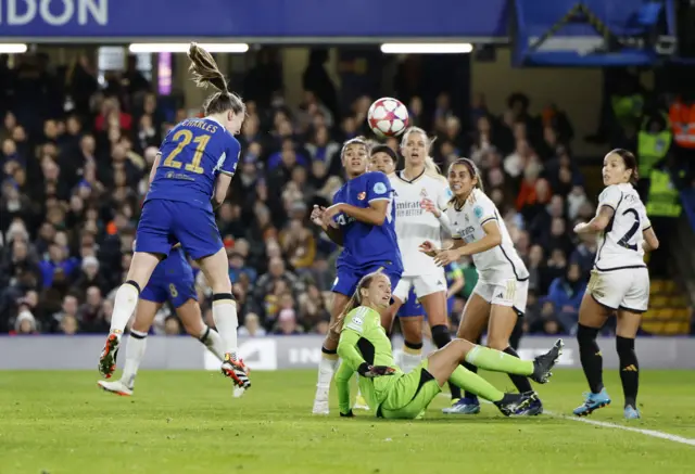 Charles heads at goal in front of a packed penalty area.