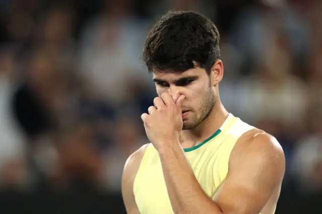 Carlos Alcaraz pinches his nose and looks down at the ground