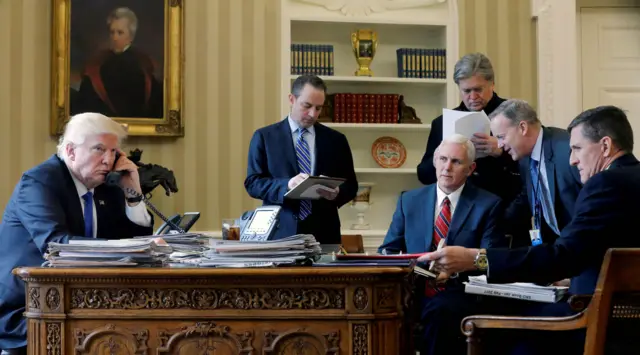 Donald Trump on the phone in the Oval Office in 2017 with five men, Sean Spicer second from the right