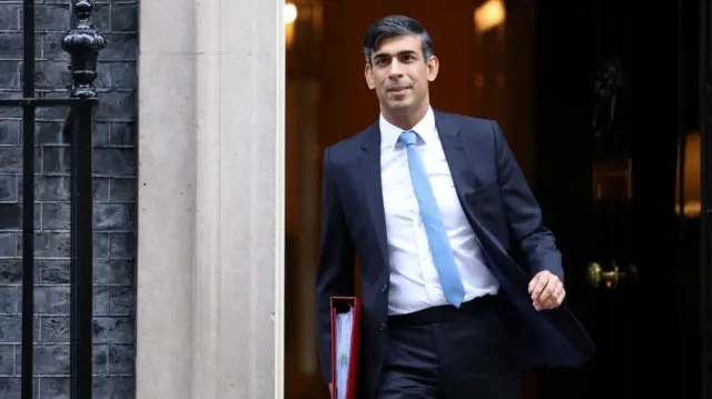 Rishi Sunak leaves No 10 by the front door holding a red file