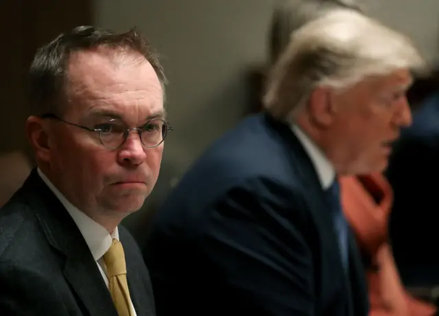 Mick Mulvaney sits next to Donald Trump as they listen to comments in the Cabinet Room at the White House